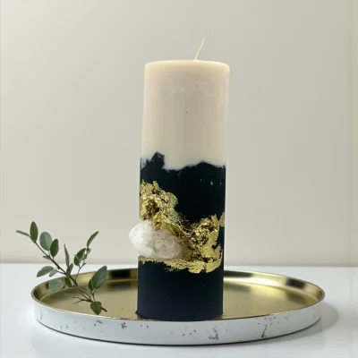 Handmade luxury soy wax candle with black and ivory layers, gold leaf accents and natural crystal, displayed on a gold tray.