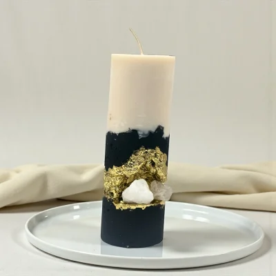 Handmade luxury soy wax candle with black and ivory layers, gold leaf accents and natural crystal, displayed on a gold tray.